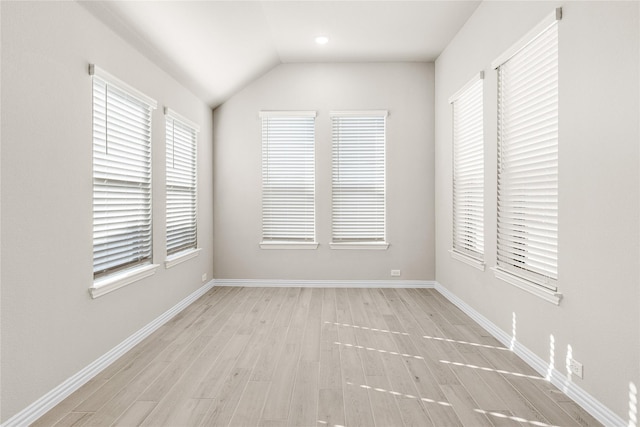 empty room featuring vaulted ceiling, light wood-type flooring, and baseboards