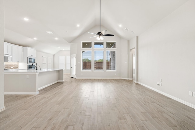 unfurnished living room featuring visible vents, light wood-style flooring, a ceiling fan, a sink, and baseboards