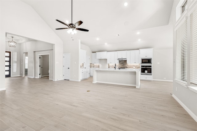 kitchen featuring black microwave, open floor plan, light countertops, and oven