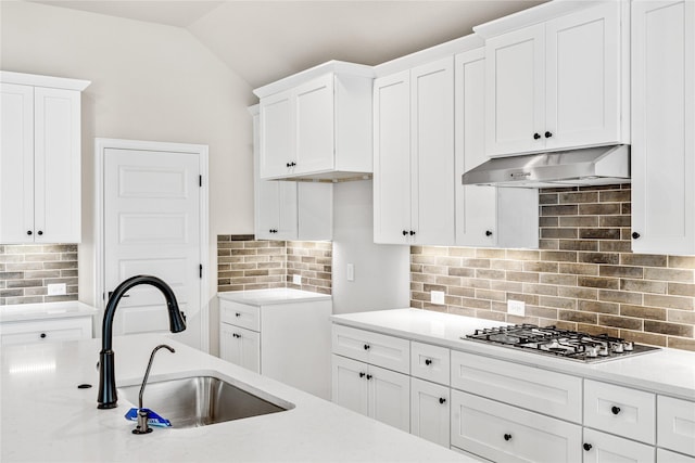 kitchen with white cabinets, light countertops, a sink, and under cabinet range hood