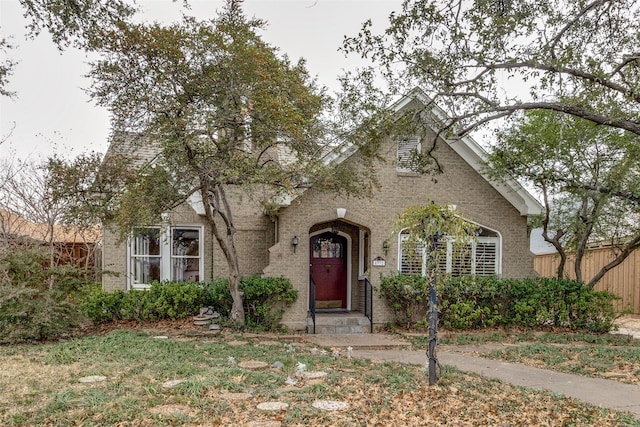 english style home with fence and brick siding