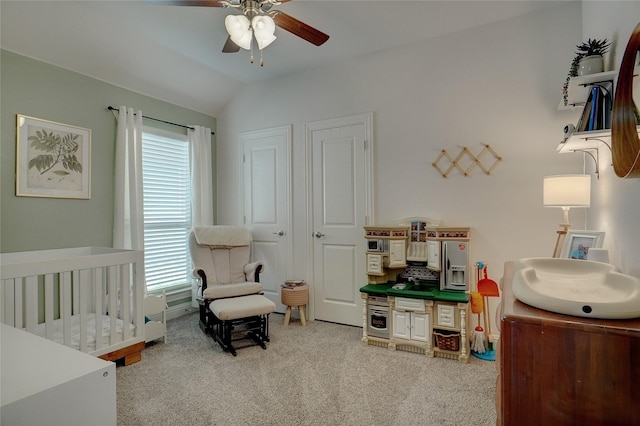 bedroom featuring vaulted ceiling, ceiling fan, a crib, and carpet