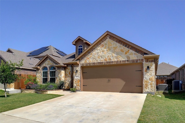 view of front of house featuring a garage, stone siding, solar panels, and cooling unit