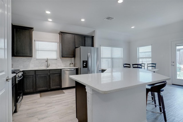 kitchen with light countertops, visible vents, appliances with stainless steel finishes, a sink, and a kitchen breakfast bar