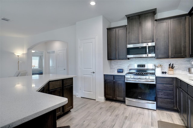 kitchen with arched walkways, stainless steel appliances, visible vents, and dark brown cabinetry