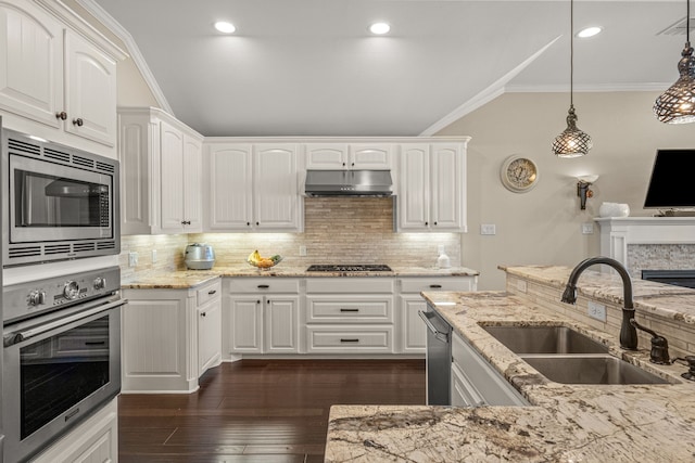 kitchen with appliances with stainless steel finishes, white cabinets, a sink, and decorative light fixtures