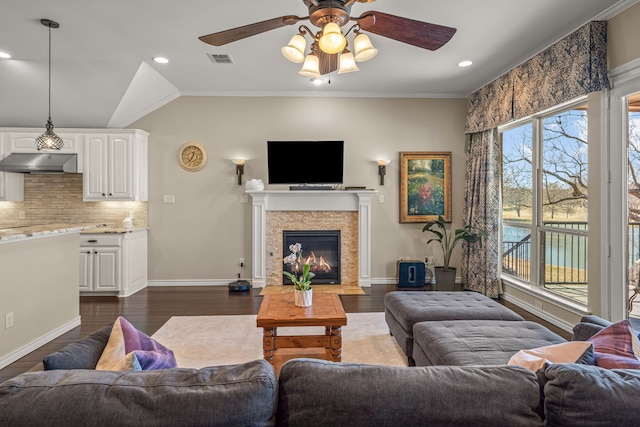 living area with baseboards, visible vents, dark wood finished floors, a fireplace with flush hearth, and vaulted ceiling