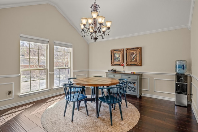 dining space with lofted ceiling, ornamental molding, dark wood-style flooring, an inviting chandelier, and a decorative wall