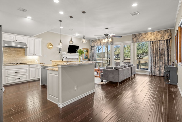 kitchen with light stone counters, open floor plan, a kitchen island with sink, under cabinet range hood, and white cabinetry