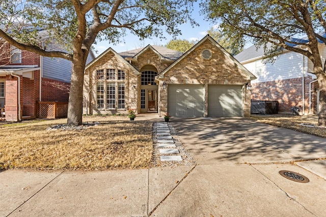 traditional-style home featuring driveway, brick siding, an attached garage, and stone siding