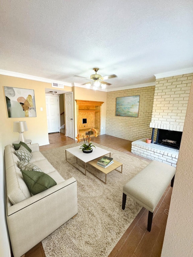 living area with visible vents, ornamental molding, wood finished floors, a textured ceiling, and a fireplace