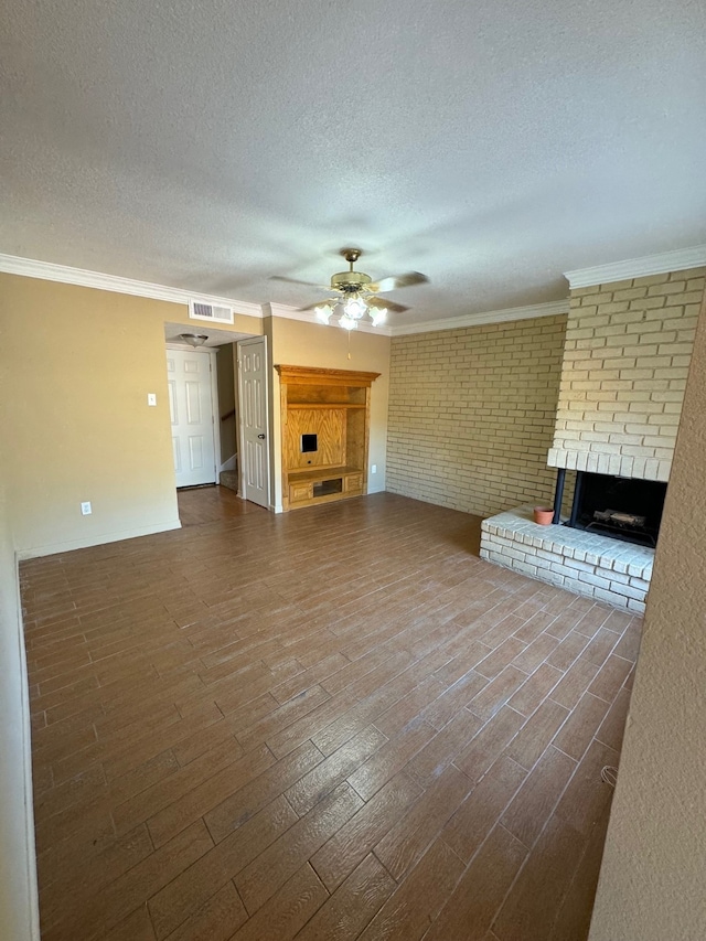 unfurnished living room with visible vents, ceiling fan, wood finished floors, crown molding, and a brick fireplace