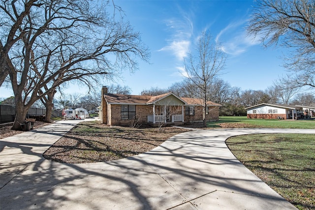 view of front of home featuring brick siding, a chimney, concrete driveway, a front yard, and a residential view