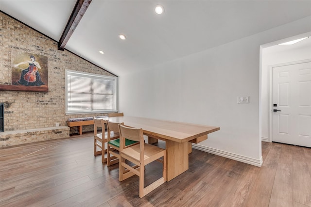 dining area featuring lofted ceiling with beams, brick wall, wood finished floors, and baseboards