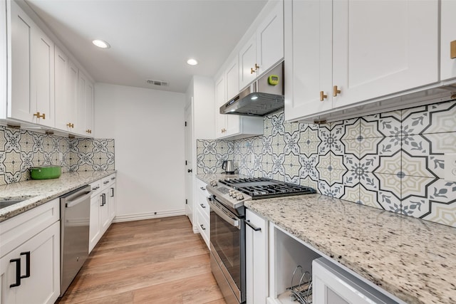 kitchen featuring light stone counters, appliances with stainless steel finishes, white cabinets, and under cabinet range hood