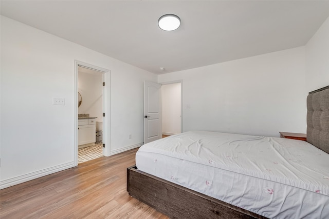 bedroom featuring baseboards, connected bathroom, and light wood finished floors