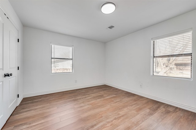 spare room featuring light wood-style flooring, baseboards, and a wealth of natural light