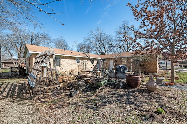 rear view of house featuring brick siding and fence