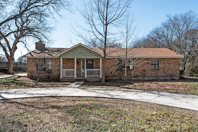 single story home featuring covered porch, a chimney, and brick siding