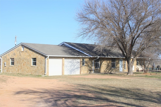 view of front facade featuring a garage, stone siding, a shingled roof, and dirt driveway