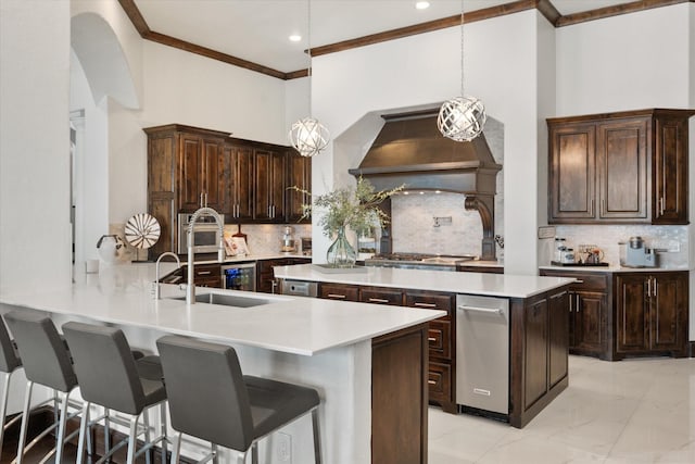 kitchen with decorative light fixtures, light countertops, dark brown cabinetry, premium range hood, and a peninsula