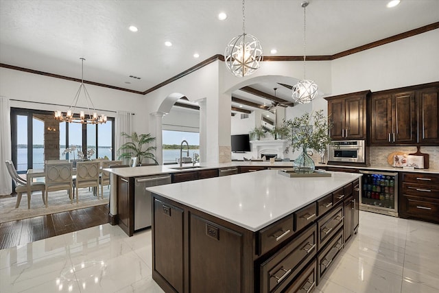 kitchen featuring beverage cooler, light countertops, a water view, and a notable chandelier