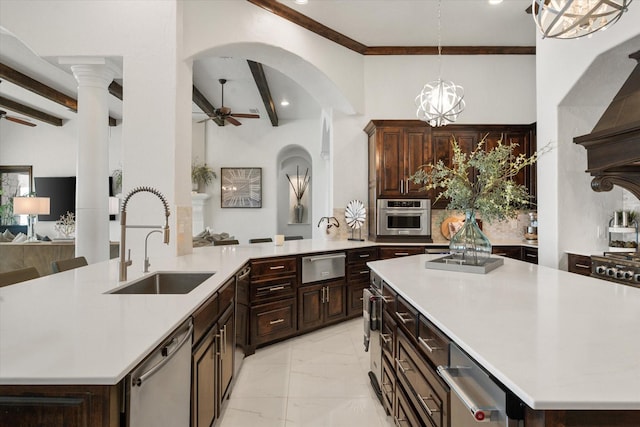 kitchen featuring ceiling fan with notable chandelier, stainless steel appliances, a sink, and light countertops