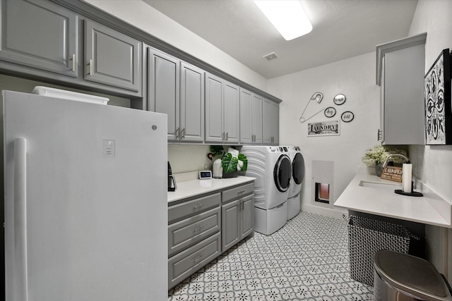 washroom with cabinet space, visible vents, a sink, independent washer and dryer, and baseboards