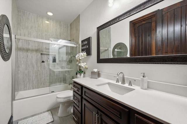 bathroom with vanity, toilet, and bath / shower combo with glass door