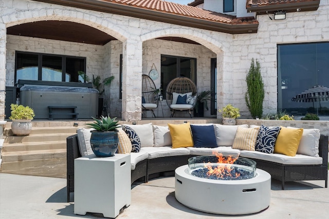 view of patio featuring a hot tub and an outdoor living space with a fire pit