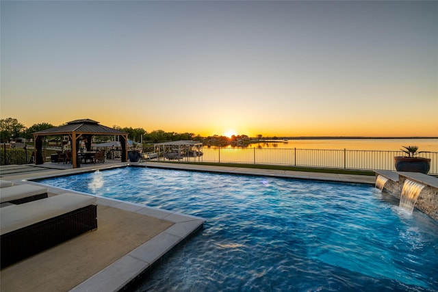 pool at dusk featuring a fenced in pool, a water view, fence, and a gazebo