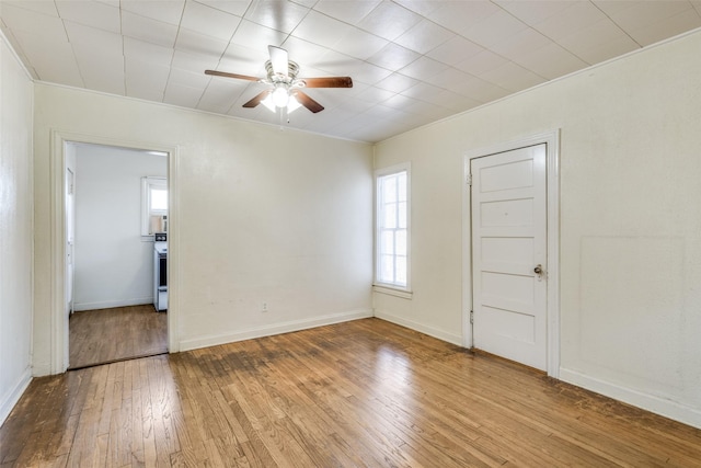 spare room featuring light wood-style floors, crown molding, ceiling fan, and baseboards