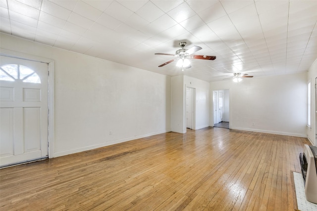 interior space featuring baseboards, ceiling fan, light wood-type flooring, and heating unit