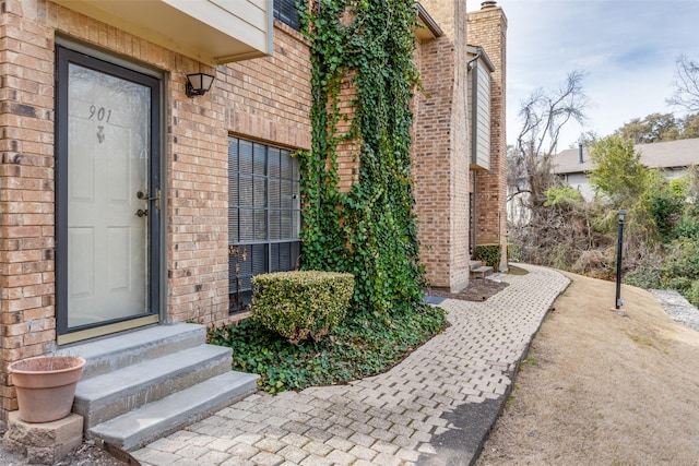 view of exterior entry featuring brick siding