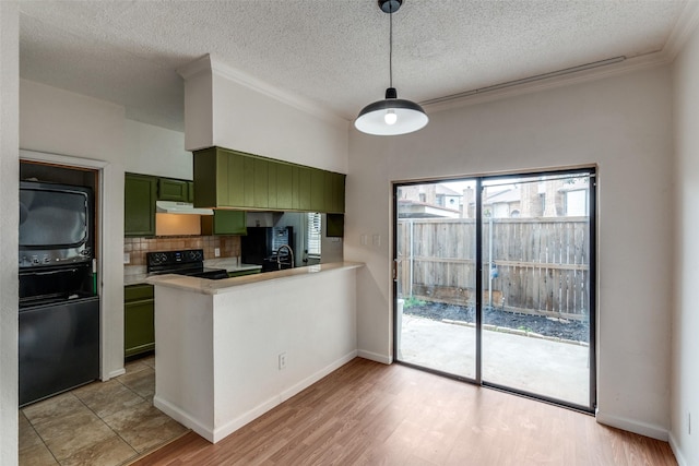 kitchen featuring green cabinetry, light wood-style flooring, black range with electric stovetop, light countertops, and backsplash