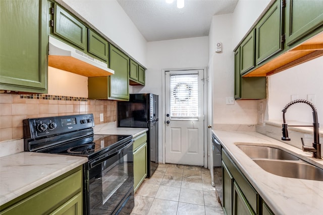 kitchen with black appliances, under cabinet range hood, green cabinets, and a sink