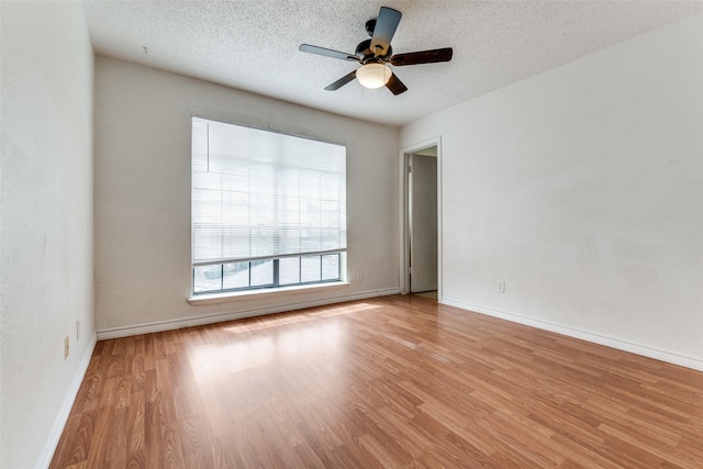 spare room with a textured ceiling, wood finished floors, and baseboards