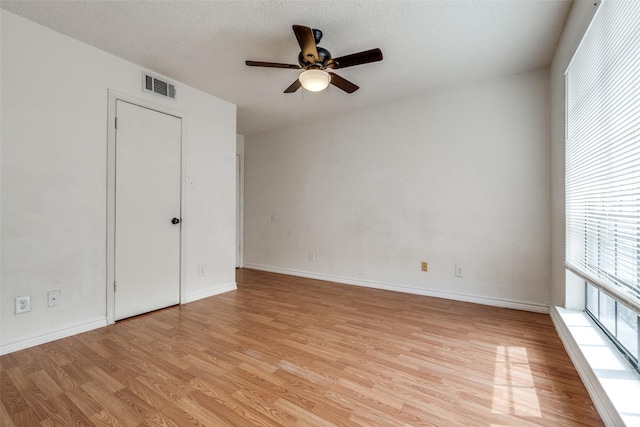 unfurnished room with visible vents, a ceiling fan, a textured ceiling, light wood-type flooring, and baseboards