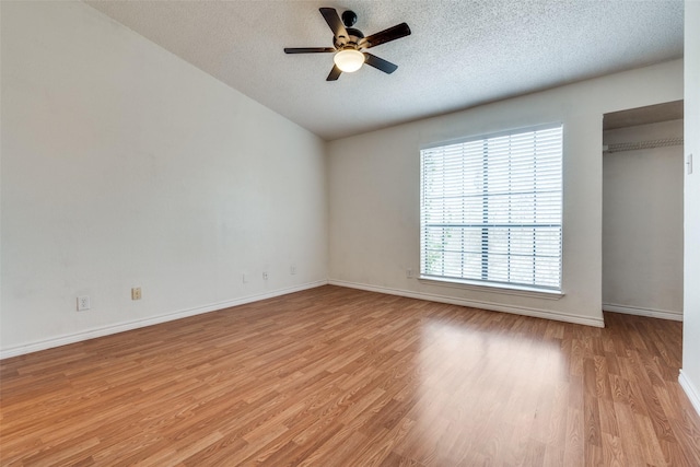 unfurnished bedroom featuring a textured ceiling, light wood-type flooring, a ceiling fan, and baseboards