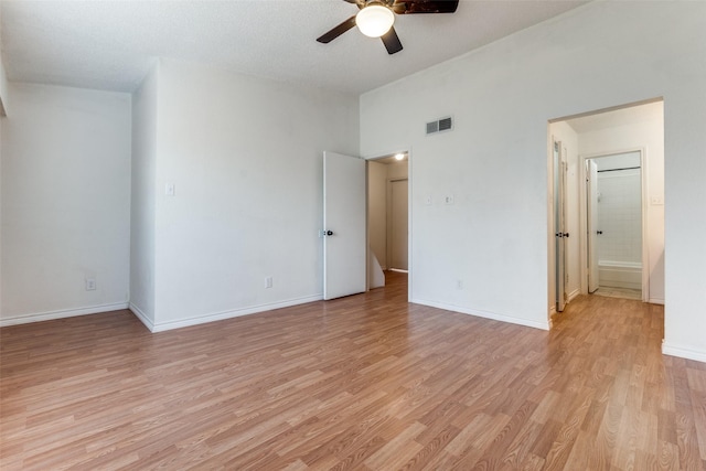 unfurnished bedroom with light wood finished floors, baseboards, visible vents, connected bathroom, and lofted ceiling