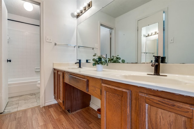 full bathroom featuring a sink, a textured ceiling, toilet, and double vanity