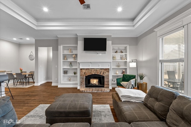 living area featuring a fireplace, a raised ceiling, visible vents, dark wood-type flooring, and baseboards