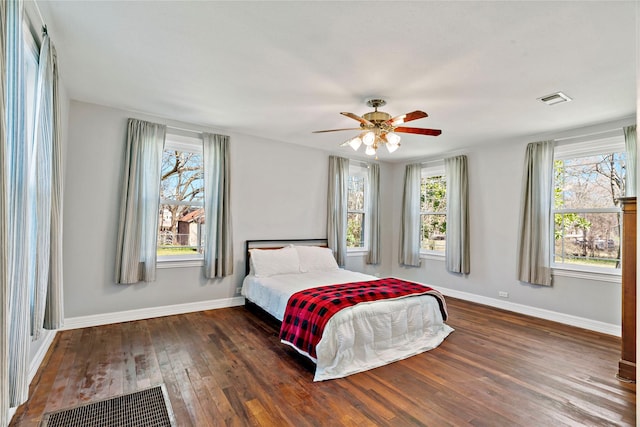 bedroom featuring dark wood-style floors, ceiling fan, visible vents, and baseboards