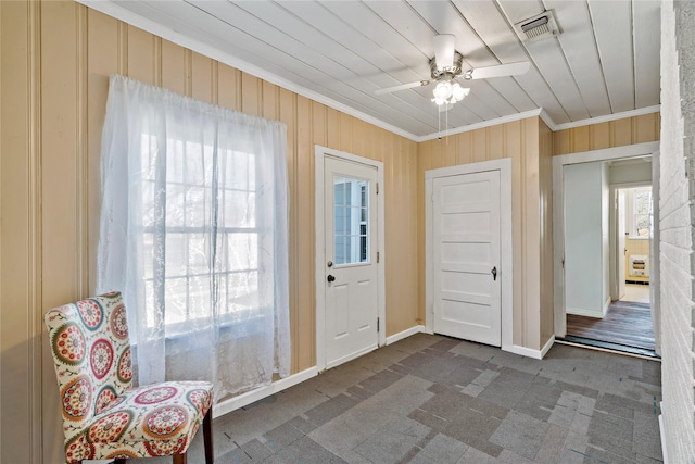 foyer entrance with ornamental molding, visible vents, baseboards, and a ceiling fan