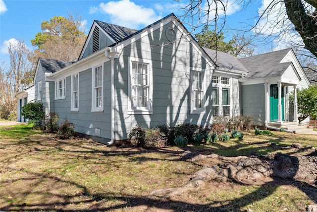 view of property exterior featuring roof with shingles and a lawn