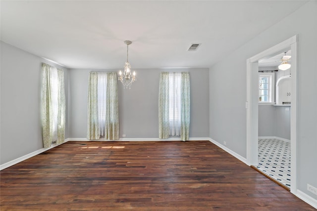 empty room featuring baseboards, a notable chandelier, visible vents, and dark wood-type flooring