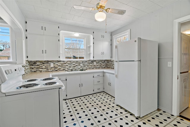 kitchen with light countertops, white appliances, a healthy amount of sunlight, and white cabinets