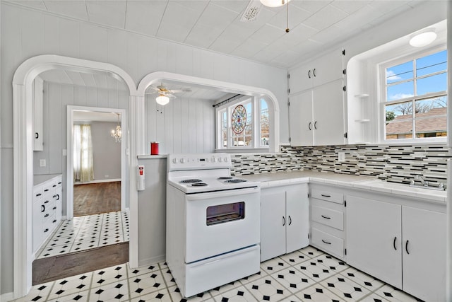 kitchen with plenty of natural light, white electric stove, white cabinets, tile countertops, and ceiling fan