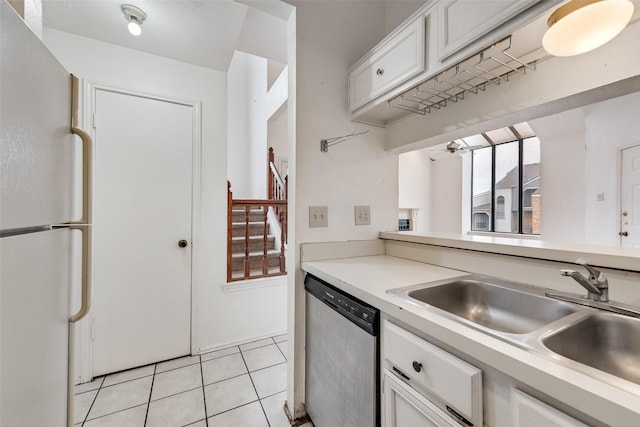 kitchen featuring a sink, white cabinetry, light countertops, stainless steel dishwasher, and freestanding refrigerator