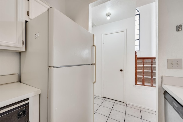 kitchen featuring light tile patterned flooring, white cabinets, light countertops, freestanding refrigerator, and dishwasher